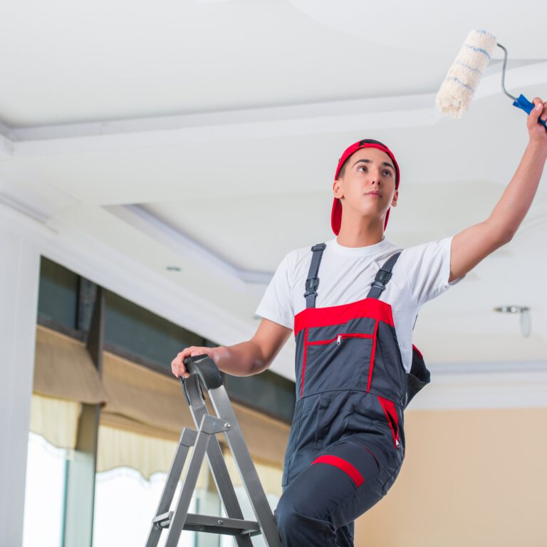 Young painter painting the ceiling in construction concept